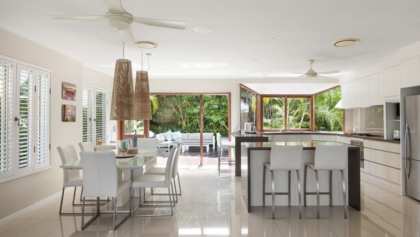 Una cucina moderna con isola centrale, mobili bianchi e un'ampia finestra che si affaccia su un rigoglioso giardino.