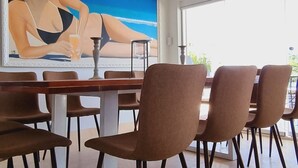 Ein Essbereich mit Tisch und Stühlen, einer Kandelaber und einem großen Gemälde einer Frau an der Wand.
