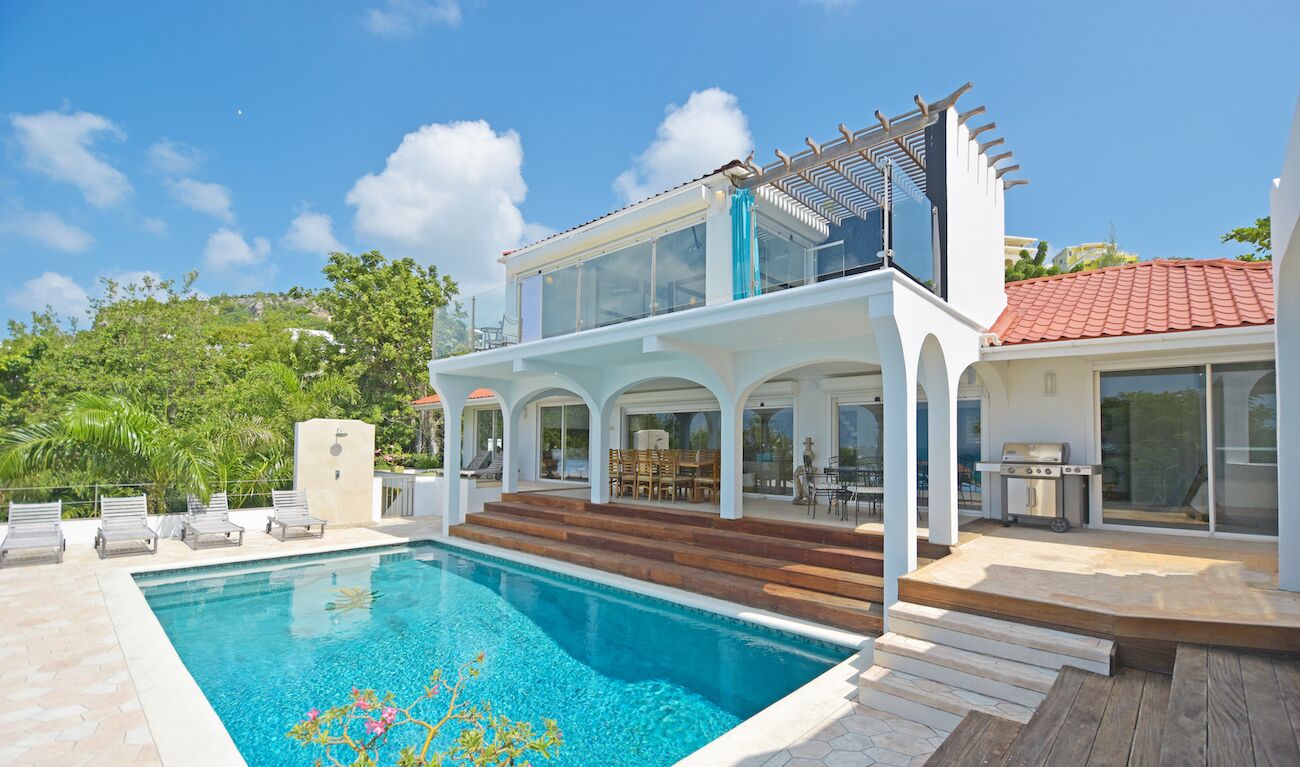 A two-story house with a swimming pool, outdoor seating, and a barbecue area.