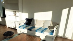 A living room with a white sofa, a wooden coffee table, and patterned rugs.
