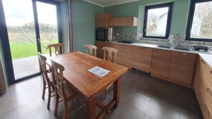 A modern kitchen with wooden cabinets, a dining table, and chairs.