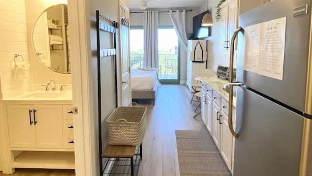 A modern kitchen with a refrigerator, a dining area with a bench, and a view of the balcony.