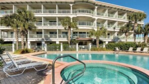 A hotel with a pool area, multiple balconies, and palm trees.