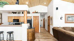 Una cocina moderna con armarios de madera, una isla central con taburetes y techo de madera.