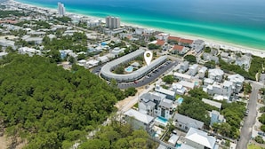 Vista aérea de un pueblo costero con una carretera curva destacada, propiedades frente a la playa y un gran hotel con piscina.