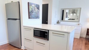 Una cocina moderna con refrigerador, horno y microondas integrados.