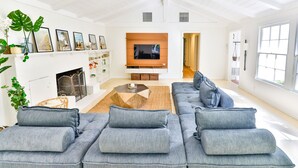 Amplia sala de estar con un sofá modular grande, chimenea, televisor de pantalla plana y un ventanal que proporciona luz natural.