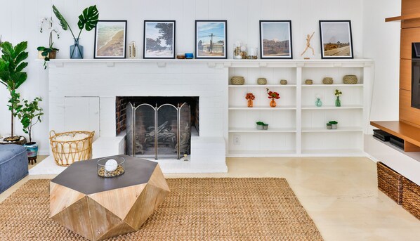 A modern living room with a white fireplace, a coffee table, and a TV stand.