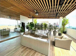 Relax in a spacious living area with a high ceiling, featuring a large sofa set and potted plants.