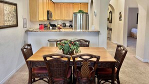 Una cocina moderna con armarios de madera, electrodomésticos de acero inoxidable y un comedor con sillas de mimbre y una mesa de madera.