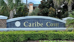 Letrero de 'Caribe Cove' con un muro de piedra y un jardín ajardinado.