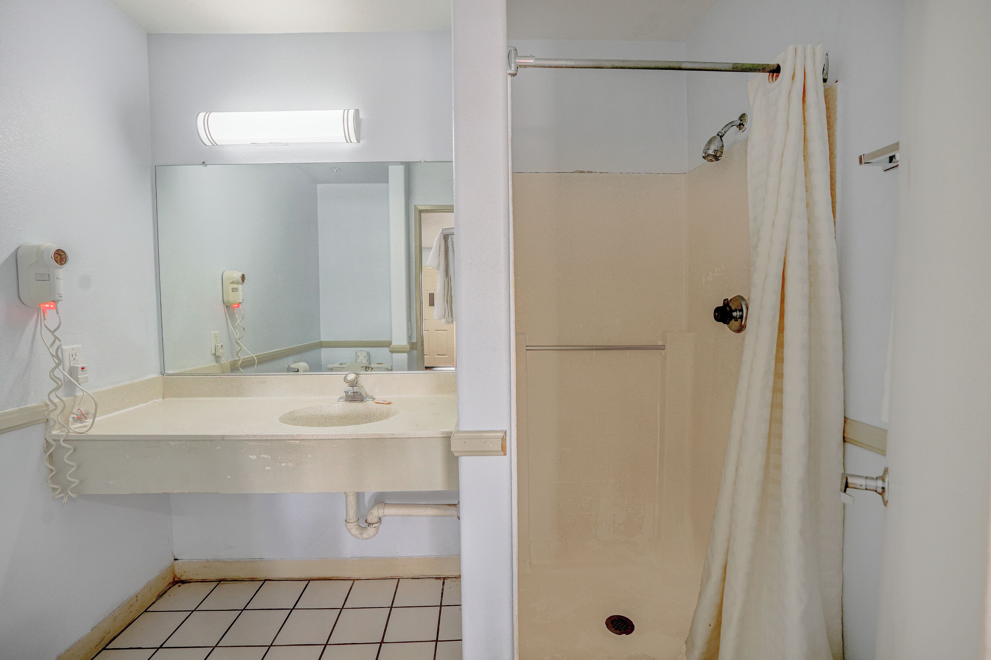 A bathroom with a white sink, mirror, and shower curtain.