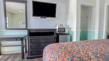 A hotel room with a bed, a dresser, a television, and a microwave.