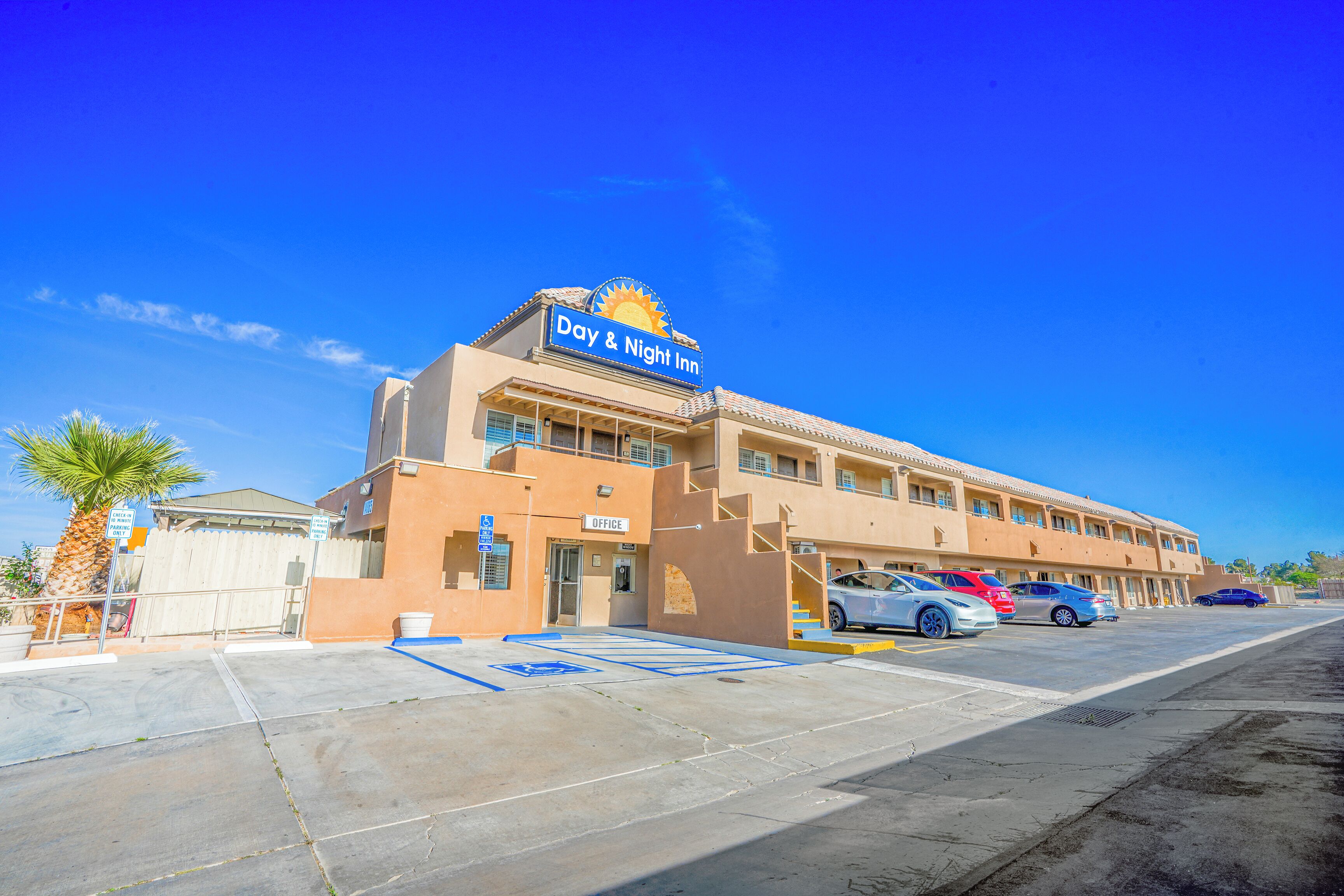 A Day & Night Inn with a parking lot, multiple cars, and a palm tree.