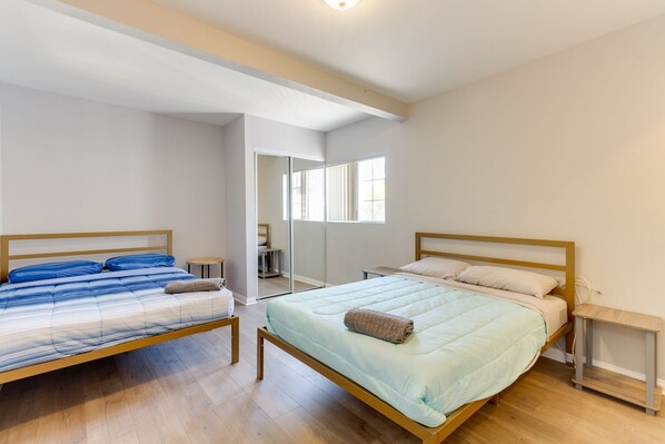 Un dormitorio con dos camas, suelo de madera y un espejo grande.