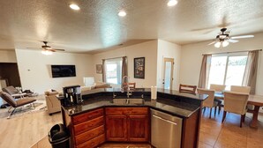 A modern kitchen with a central island, built-in appliances, and a dining area with a view.