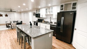 A spacious kitchen with a central island, white cabinets, and a black refrigerator.