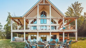 Une maison en bois à deux étages, dotée d’un balcon, d’un espace extérieur aménagé pour s’asseoir et d’une grande fenêtre.
