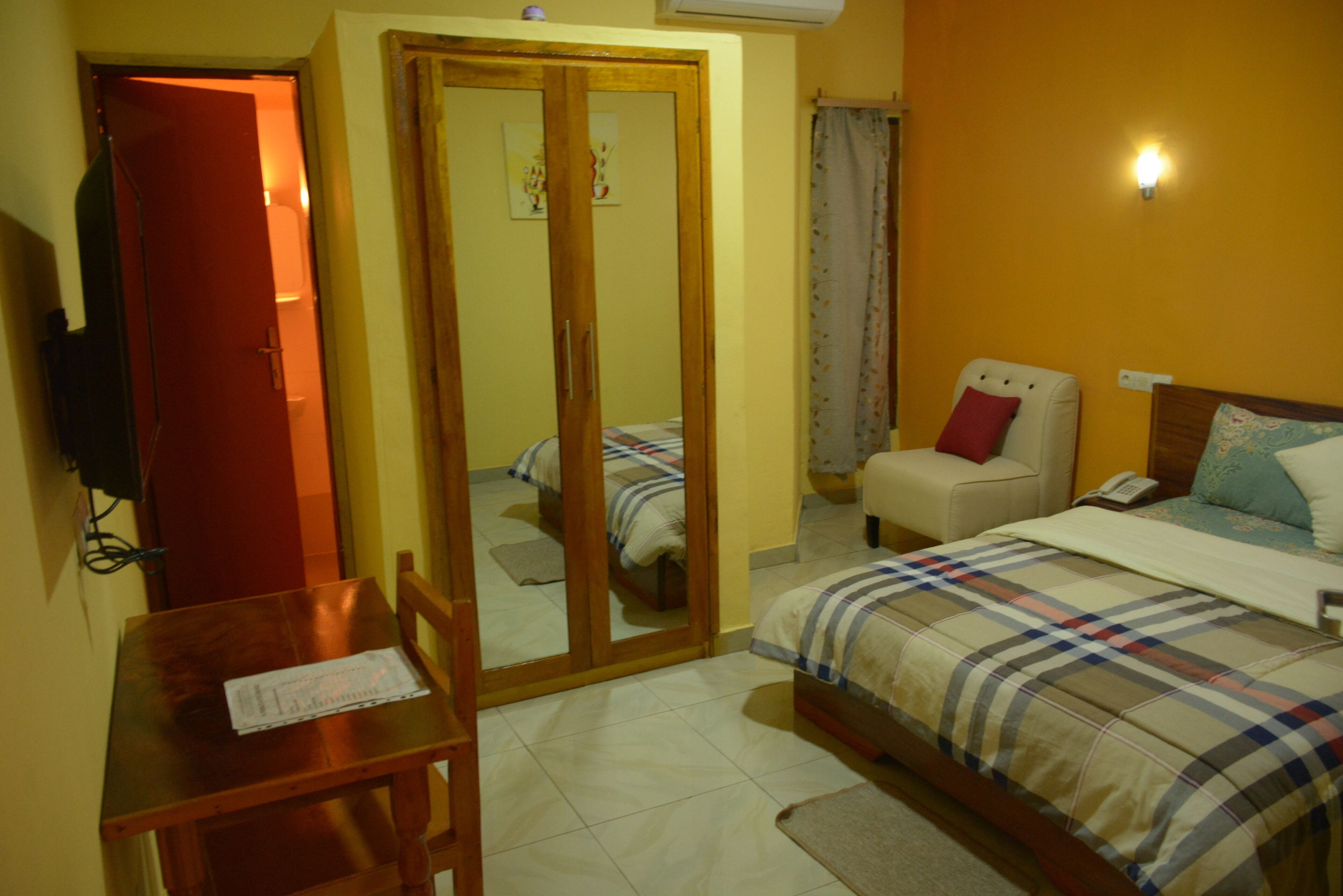 Habitació d'hotel amb llit, cadira, escriptori i armari.