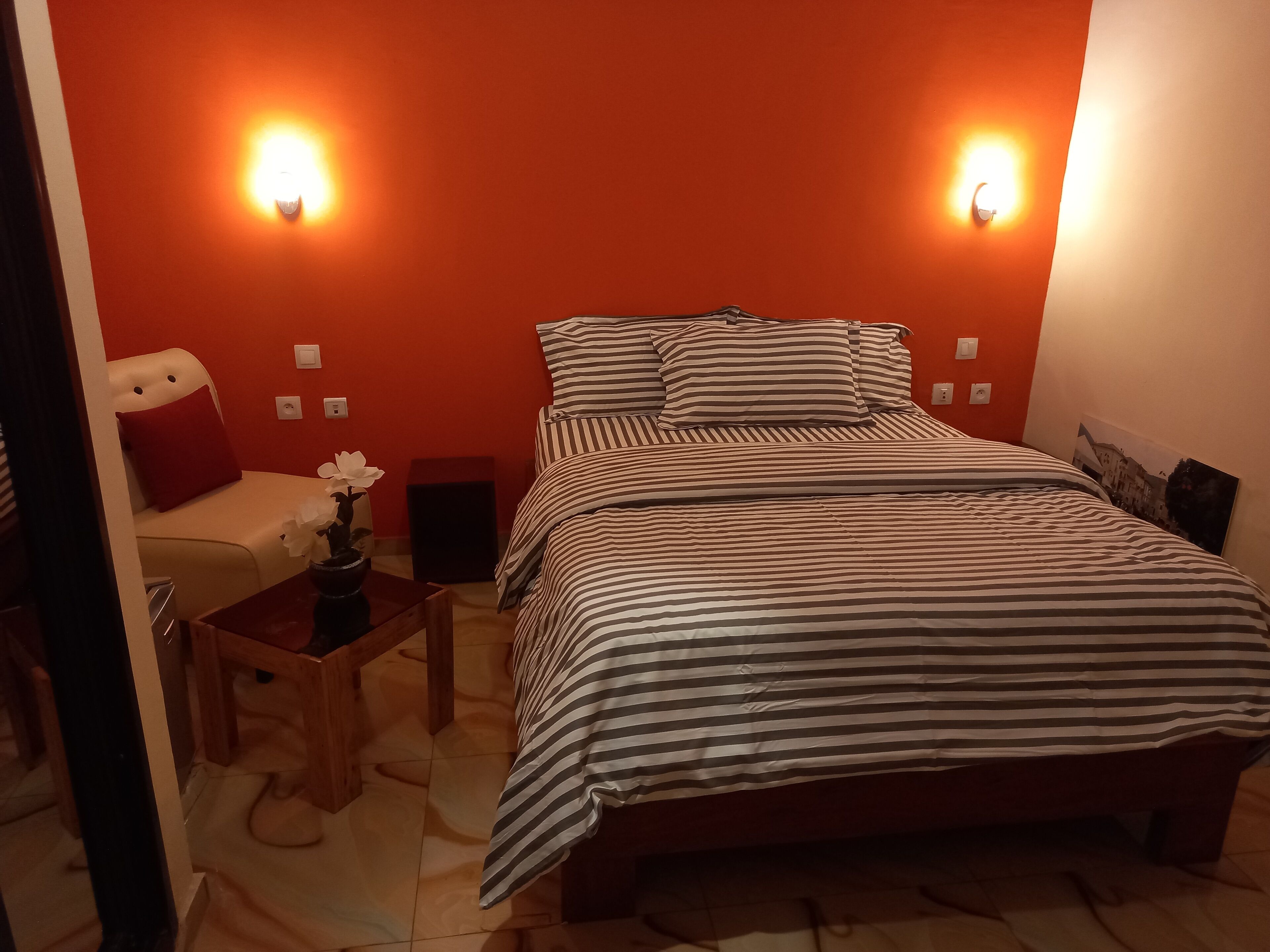 A bedroom with a bed, bedside tables, a chair, and a small table with a vase.