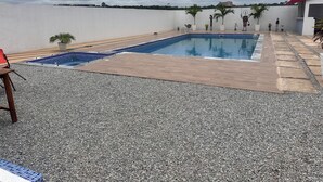 A rooftop swimming pool with a pebble deck, surrounded by potted plants and a red-roofed building. - Florence Hotel Firenze Yamoussoukro (Yamoussoukro)