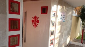 A hallway with a white door featuring red decorative elements, a tiled floor, and a brown doormat. - Florence Hotel Firenze Yamoussoukro (Yamoussoukro)