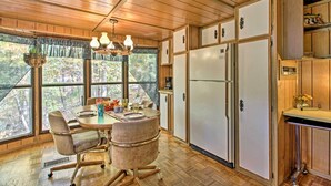 Eine Küche mit Holzausstattung, einem Kühlschrank und einem Essbereich mit Stühlen und einem Tisch.