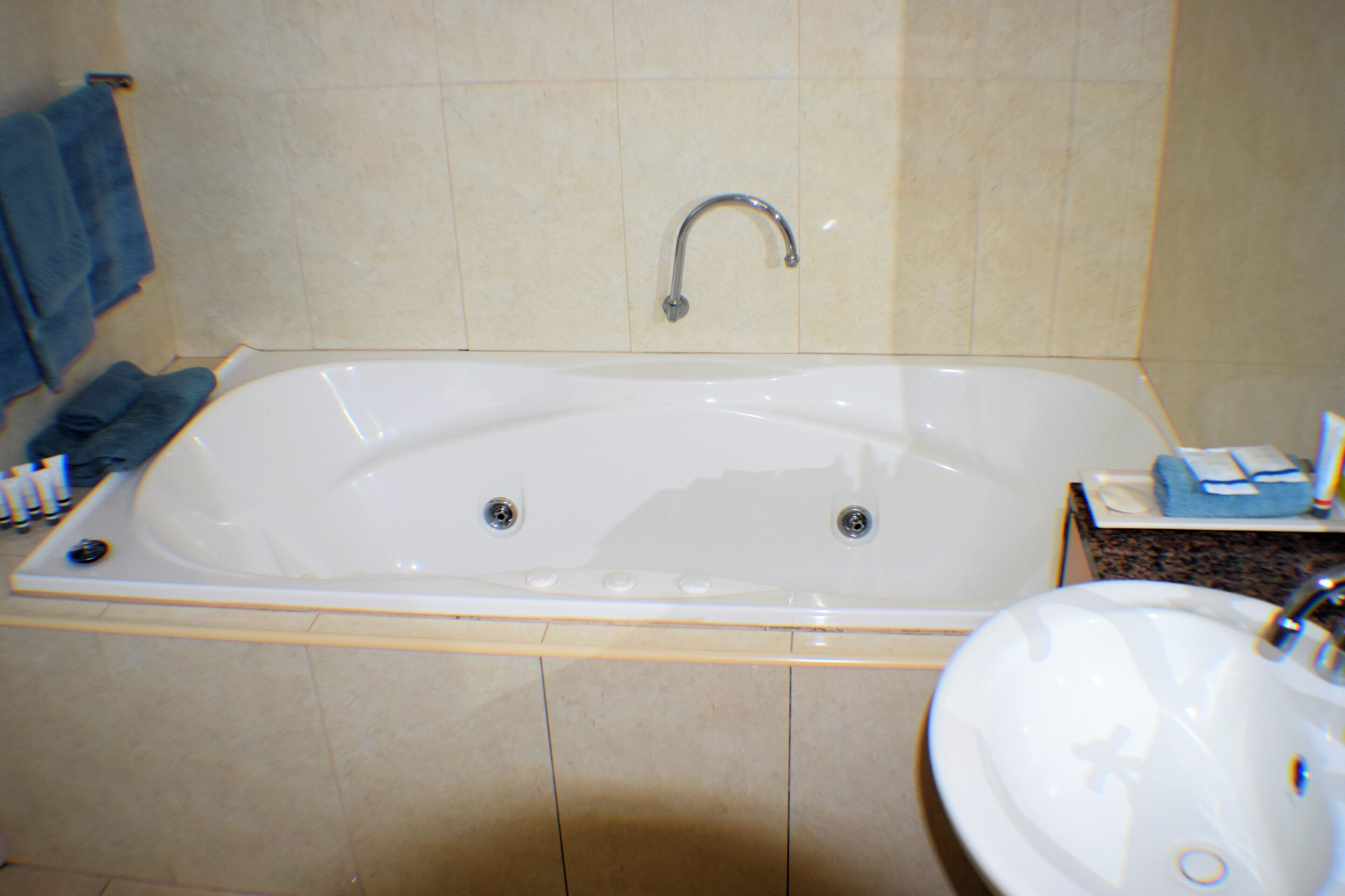 A bathroom with a bathtub, a sink, and a towel rack.