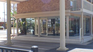Un edificio con fachada de vidrio, columnas y un balcón.
