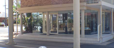 A building with a glass facade, columns, and a balcony.