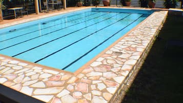 Una piscina al aire libre, sillones reclinables de piscina