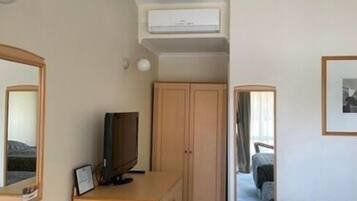 A hotel room with a desk, a television, a wardrobe, and a bed.