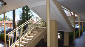 Una escalera con peldaños color beige y barandales blancos, que lleva a un nivel superior.