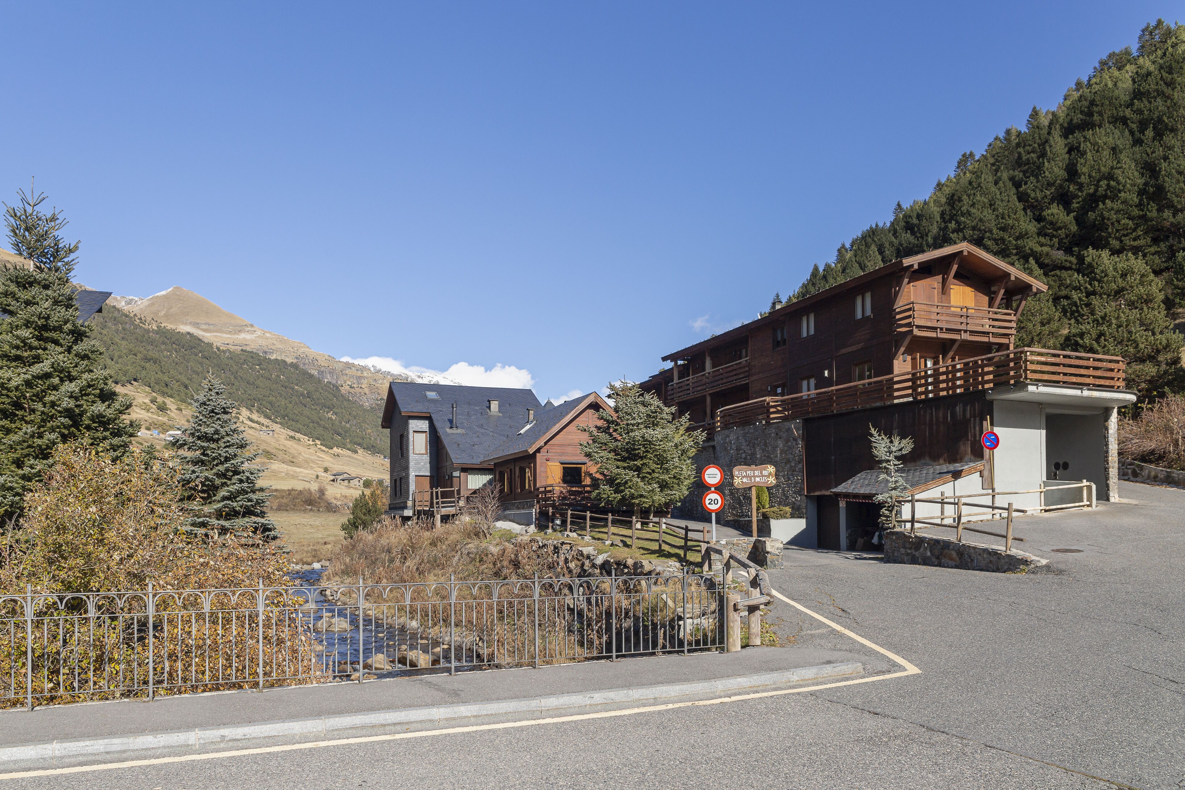 A mountain lodge with a wooden exterior, a stone entrance, and a clear view of the surrounding mountains.