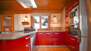 A modern kitchen with red cabinets, stainless steel appliances, and a wooden ceiling. - 𓃹 By Grandvalira: 2BD Duplex & Free Parking (Canillo)