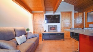 A living room with a sofa, a fireplace, wooden walls, and a TV. - 𓃹 By Grandvalira: 2BD Duplex & Free Parking (Canillo)