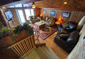 Relax in the inviting living room with a comfortable seating area, staircase, and framed artwork.