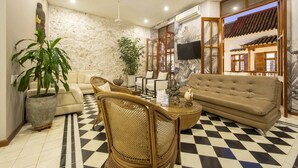 Uma sala de estar com piso xadrez, um sofá, uma mesa de centro e uma televisão.