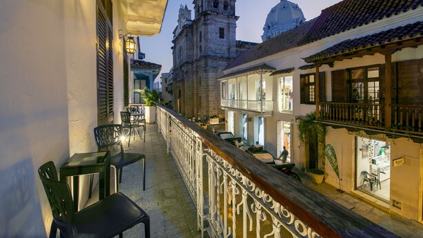 Varanda com área de estar ao ar livre, vista de edifícios históricos e grade com detalhes decorativos.