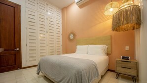 Quarto com cama, mesa de cabeceira, guarda-roupa e luminária na parede.