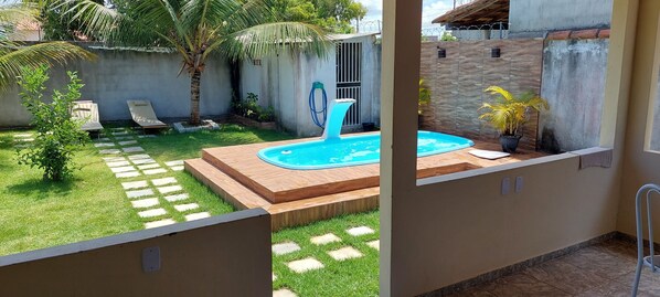 A backyard with a swimming pool, a palm tree, and a small garden area.