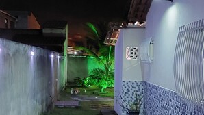 A narrow pathway with stepping stones leading to a building with a tiled exterior and a white wall.