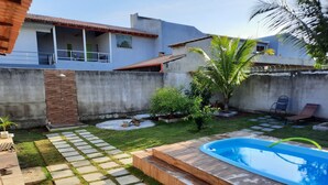 A backyard with a swimming pool, stone pathway, and a small garden area.