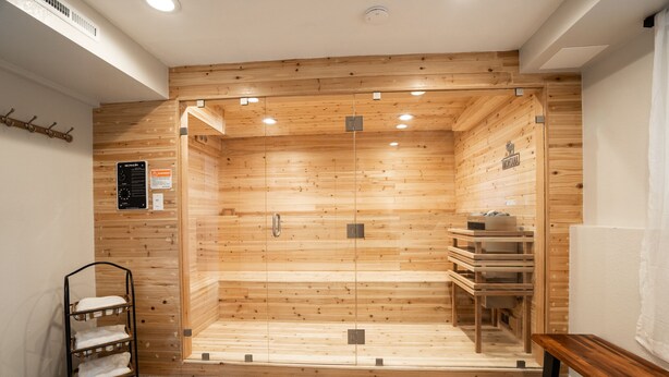 A sauna room with wooden walls, a bench, and a towel rack. - Big Sky Hotelier - Outstanding Sauna House (Billings)