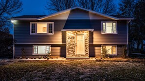 A two-story house with a stone entrance, numbered 245, and a well-lit front yard. - Big Sky Hotelier - Outstanding Sauna House (Billings)