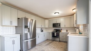A modern kitchen with white cabinets, stainless steel appliances, and a patterned backsplash. - Big Sky Hotelier - Outstanding Sauna House (Billings)