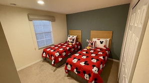 A bedroom with two beds, each with Mickey Mouse themed bedding.