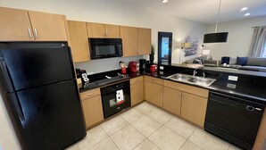 Una cocina moderna con electrodomésticos negros, armarios de madera y encimera negra.