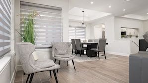 A modern dining area with a table and chairs, a potted plant, and a view of the kitchen.