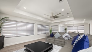 A modern living room with a sofa, a coffee table, and a ceiling fan.